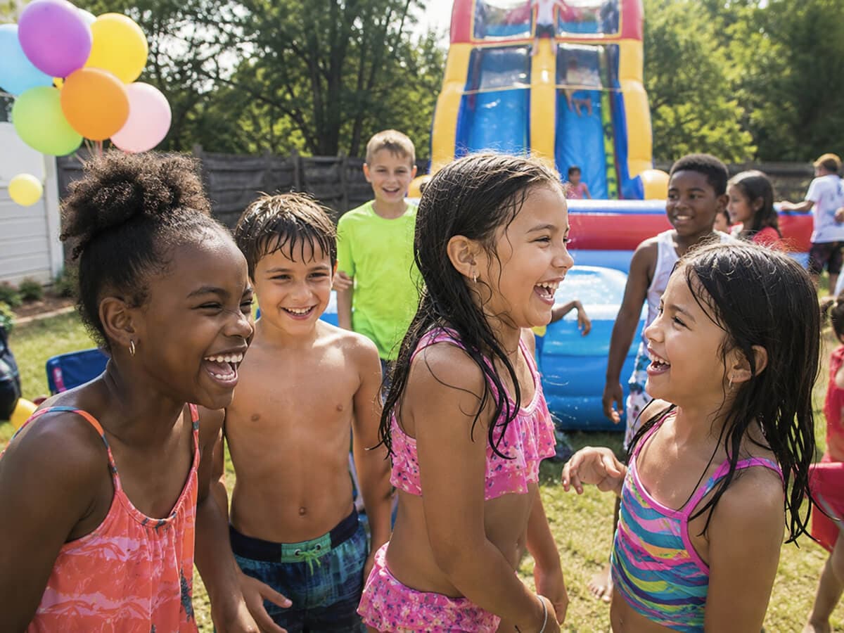Kids enjoying an inflatable water slide rental on a sunny day